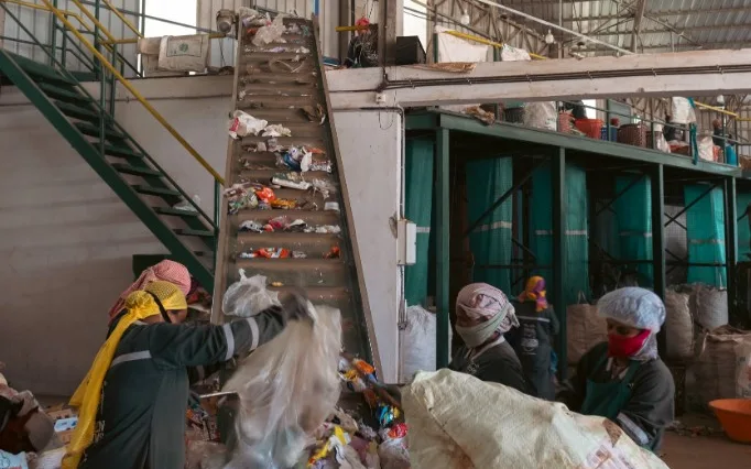 Workers sorting collected waste on a conveyor line at the Kasaragod material recovery facility
